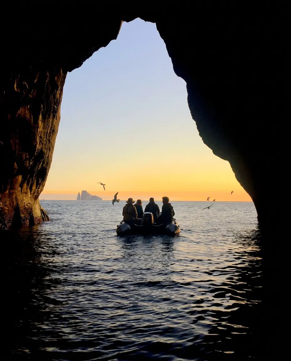 Expedition boat leaving a sea cave at sunset
