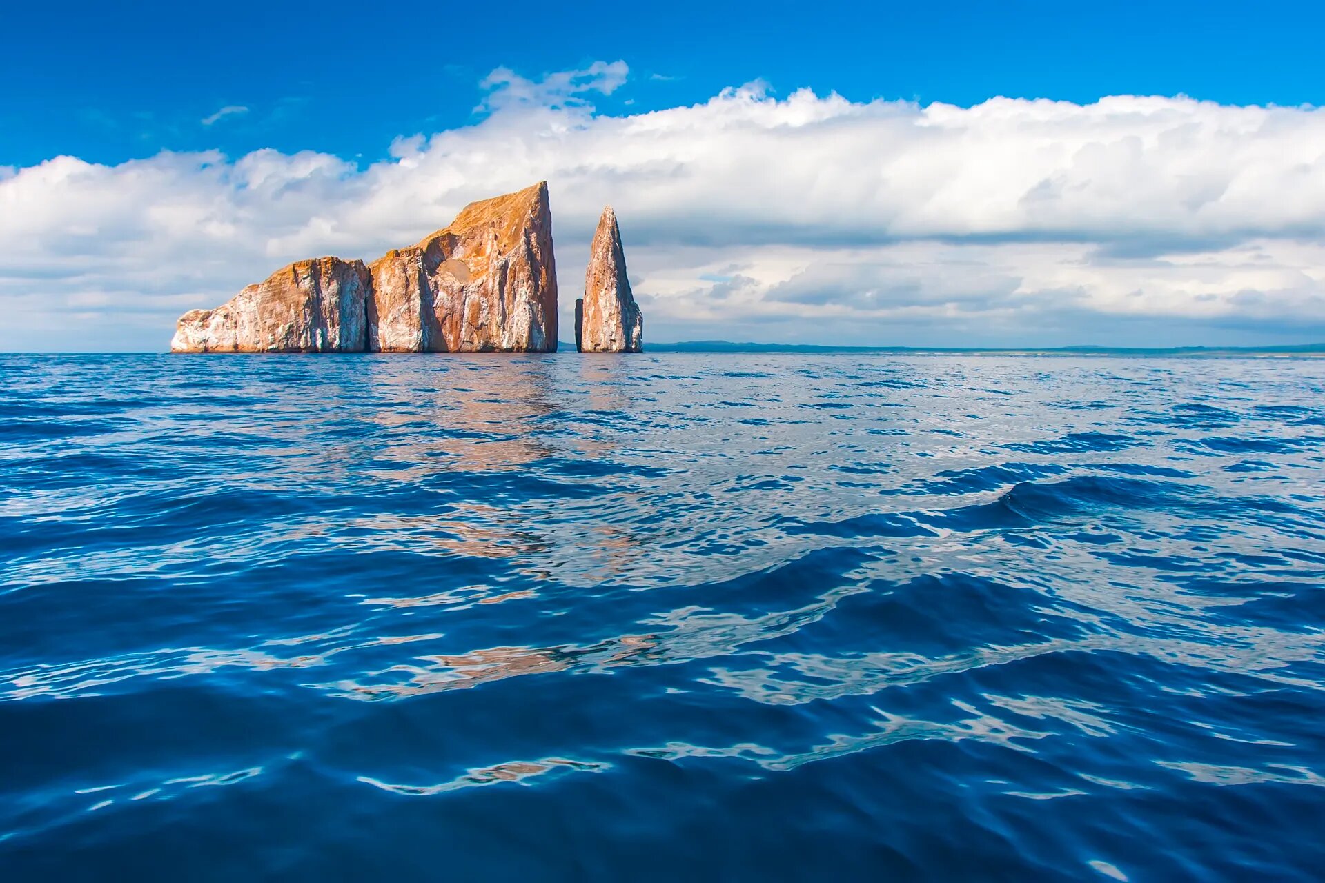 Steep rock formation rising from deep blue sea